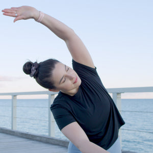 Leah Itsines calm and stretching on a jetty with ocean water behind in Adelaide, South Australia